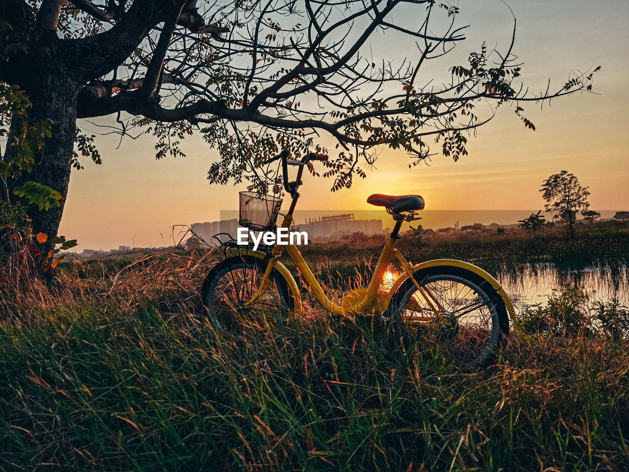 Bicycle on field against sky during sunset