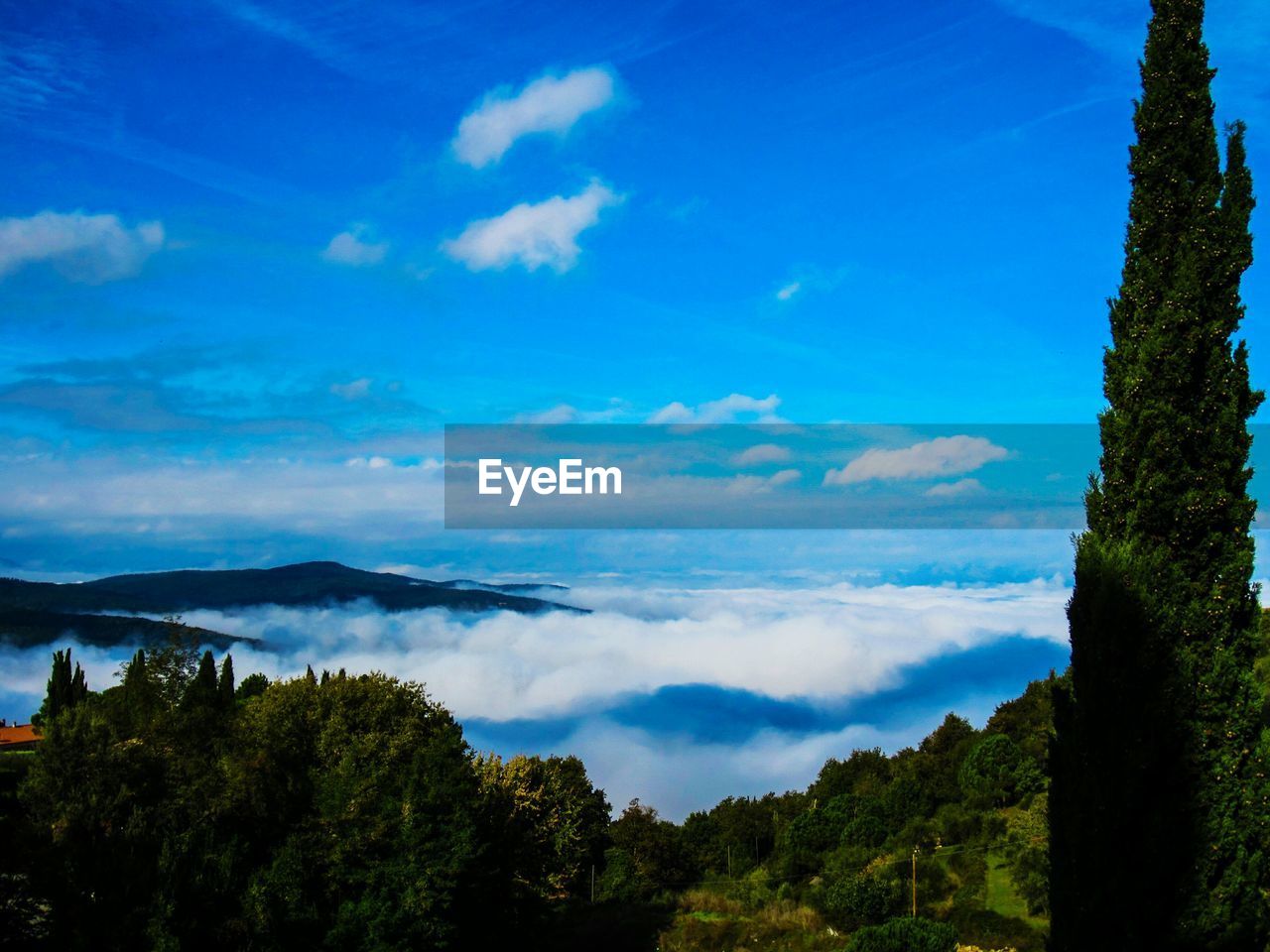 Scenic view of cloud covered mountains against blue sky