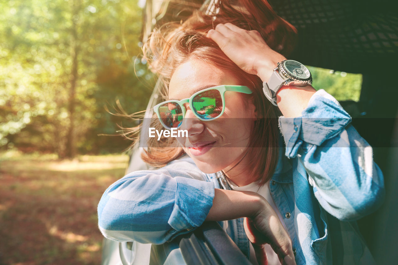 Young woman wearing sunglasses traveling in car