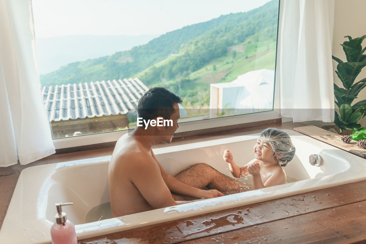 side view of man washing hands in bathtub at home