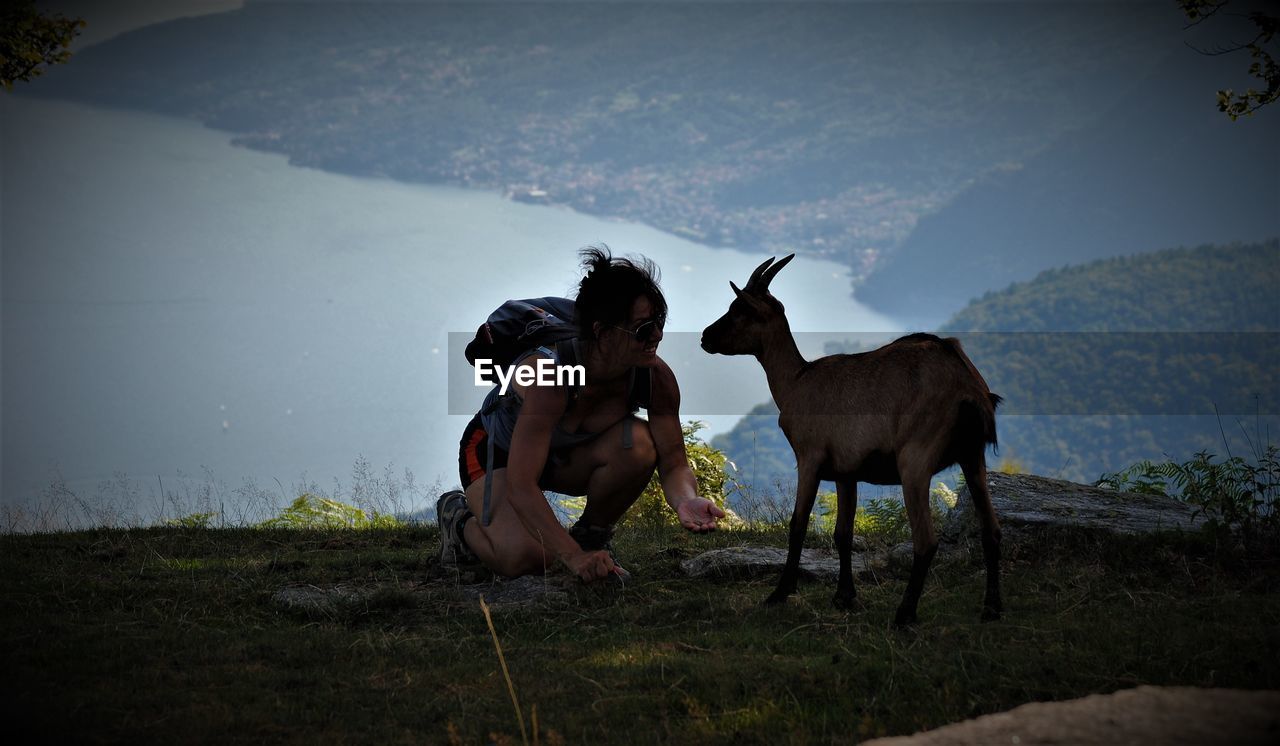 Female hiker with goat on mountain against sea