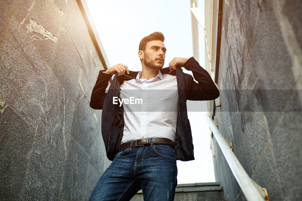 Businessman looking away while standing amidst wall