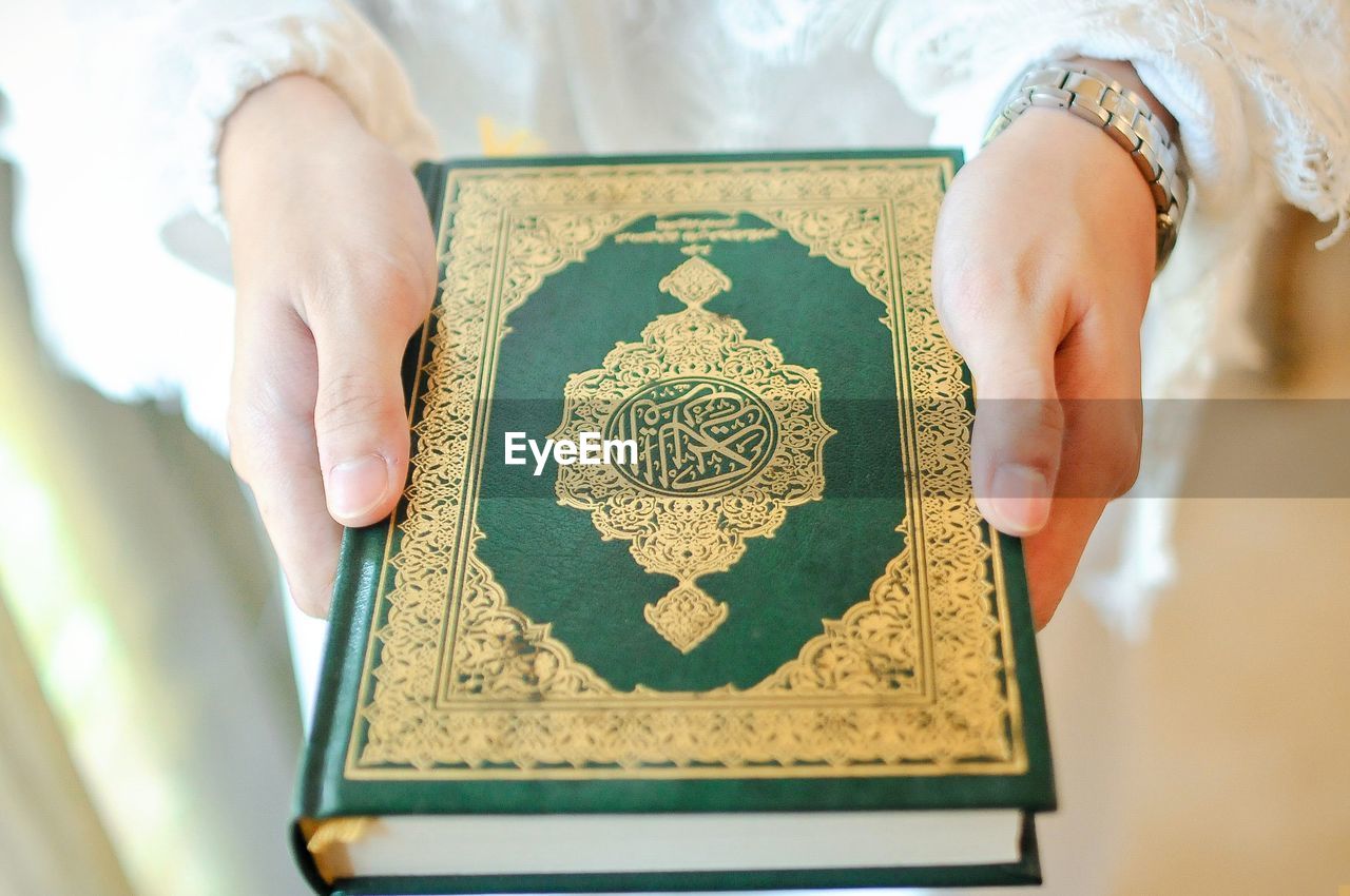 Midsection of woman holding holy quran