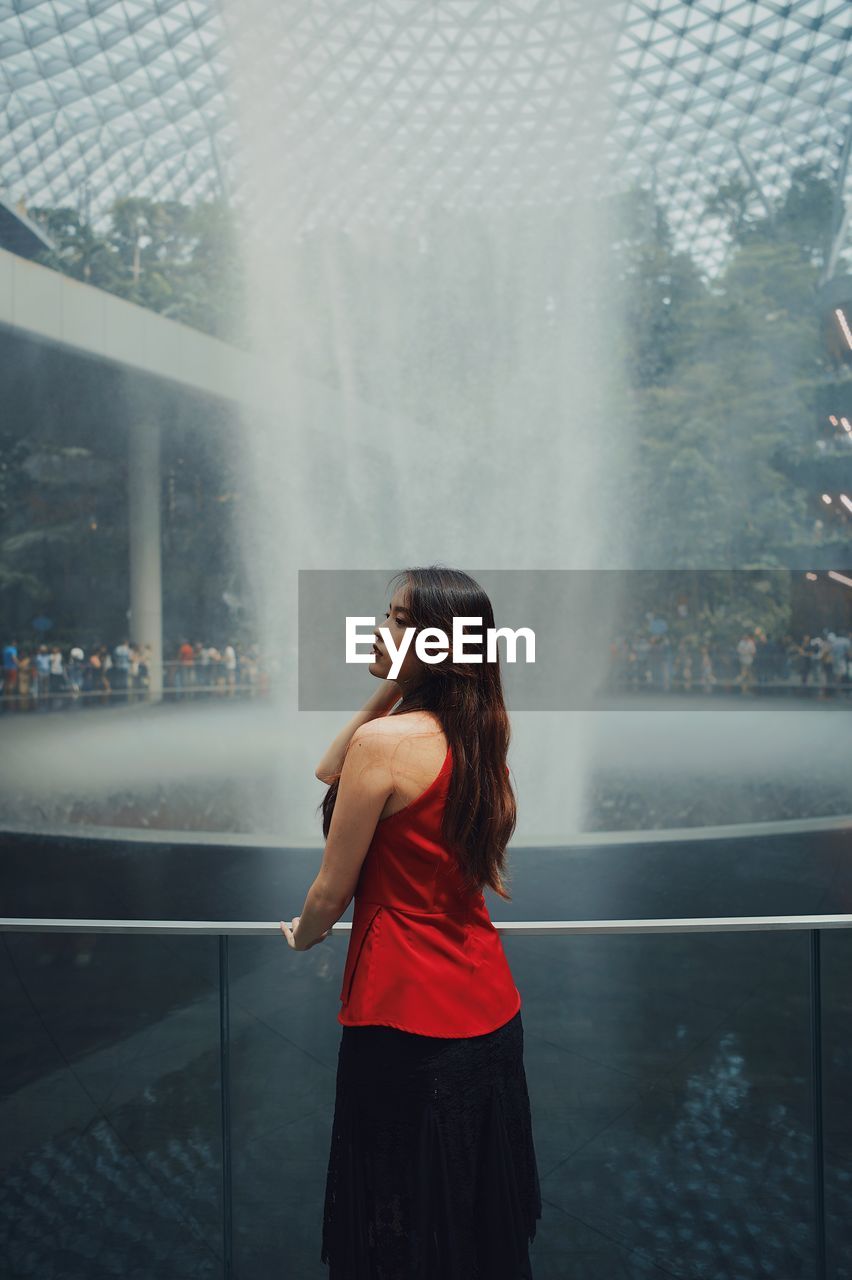 Rear view of woman standing by fountain outdoors