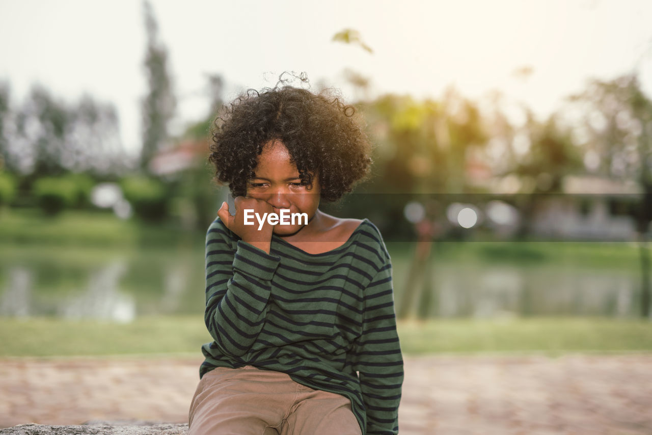 Sad boy crying while sitting at park