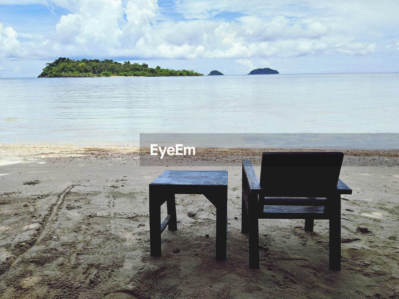 CHAIRS AND TABLE ON BEACH AGAINST SKY