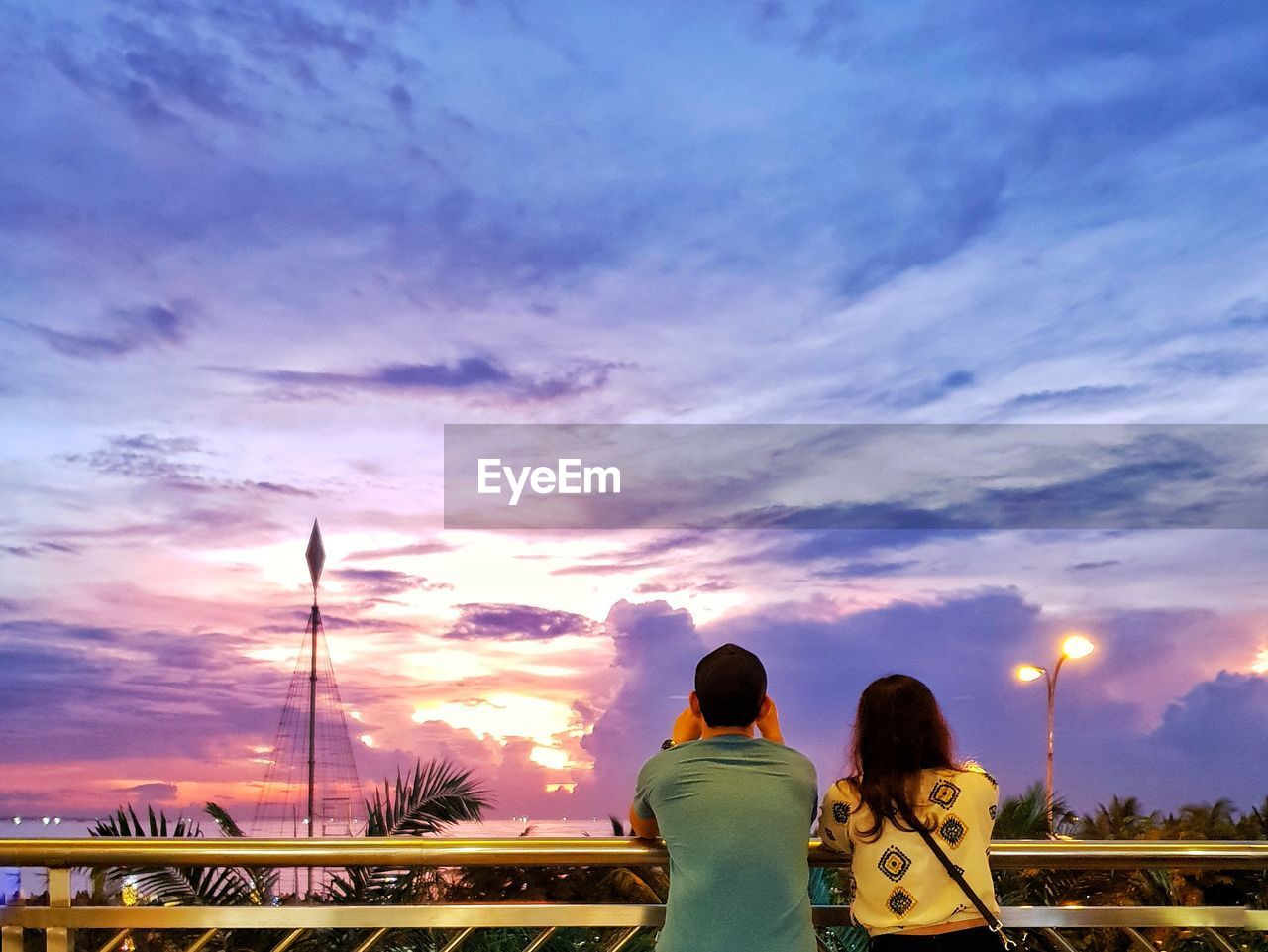 REAR VIEW OF COUPLE WALKING AGAINST SKY
