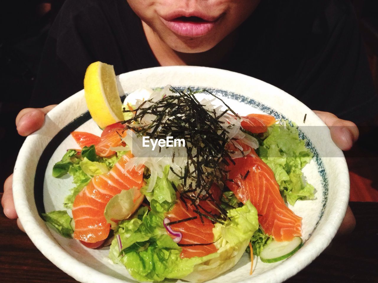 High angle midsection of man holding sashimi with cabbage in plate at home