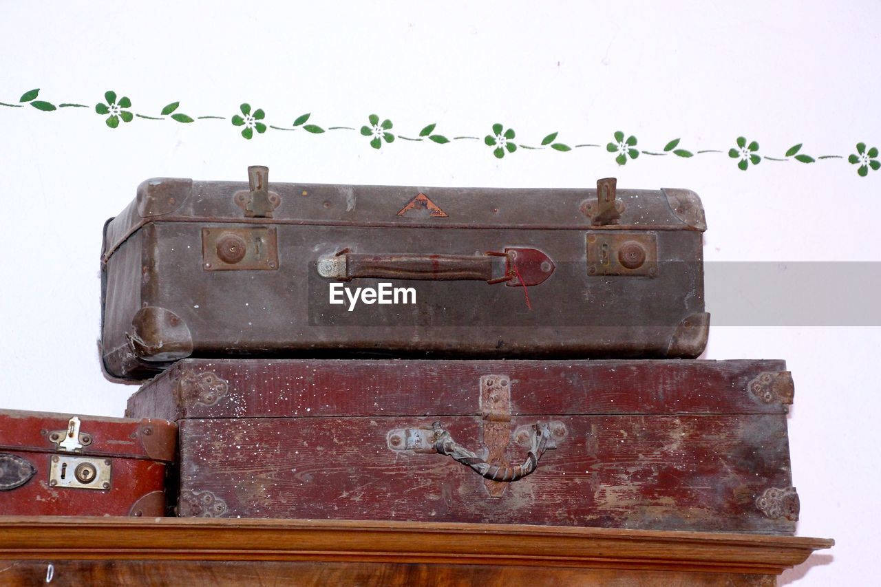 Low angle view of old luggage on wood against wall at home