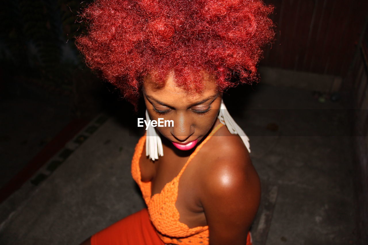 Woman with curly hair wearing tank top at night