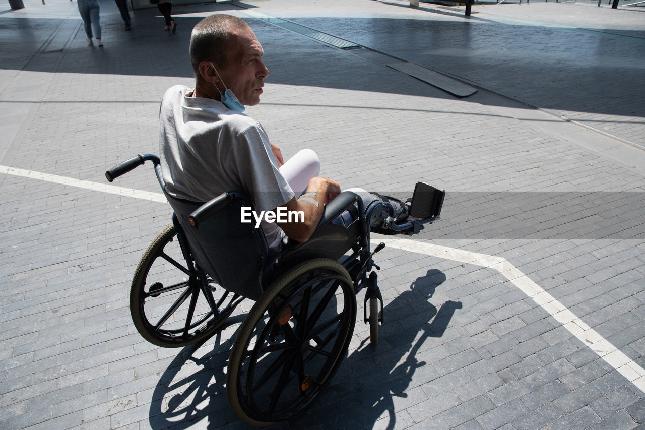 Middle-aged man with a broken leg in a cast in a wheelchair on a walk