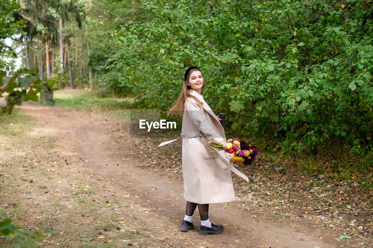 plant, full length, women, one person, adult, dress, nature, tree, young adult, green, smiling, happiness, standing, fashion, lifestyles, female, clothing, flower, emotion, walking, portrait, day, leisure activity, woodland, outdoors, person, growth, bride, hairstyle, wedding dress, land, front view, forest, looking at camera, long hair, holding, autumn, flowering plant, spring, footpath, casual clothing, freshness, beauty in nature, fruit, food, wellbeing, looking