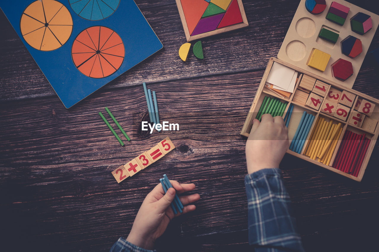 hand, art, one person, wood, holding, high angle view, creativity, indoors, leisure activity, directly above, multi colored, table, childhood, women, adult, blue, child, activity, lifestyles