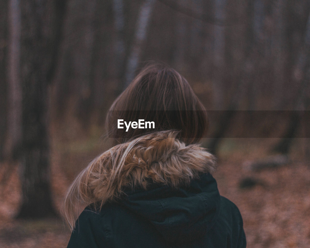 REAR VIEW OF WOMAN WALKING IN FOREST DURING WINTER