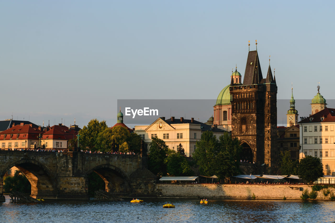 ARCH BRIDGE OVER RIVER AMIDST BUILDINGS AGAINST CLEAR SKY