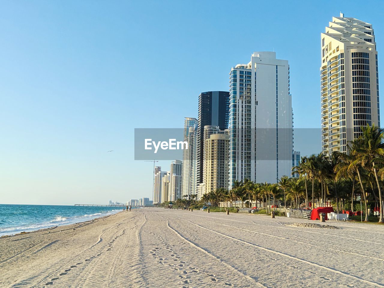 Modern buildings by sea against clear blue sky