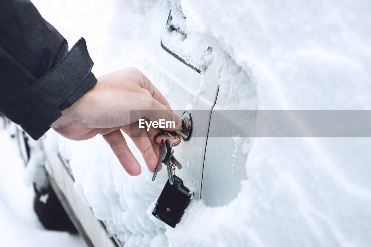 Cropped image of hand opening car door with key