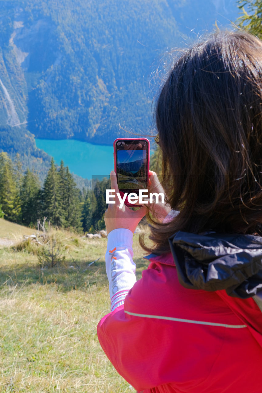 REAR VIEW OF WOMAN PHOTOGRAPHING CAMERA ON MOUNTAIN