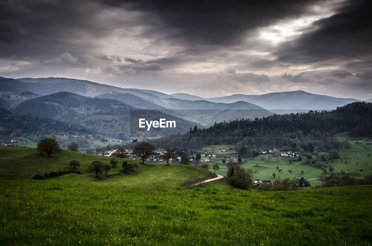 Scenic view of village and mountains against sky