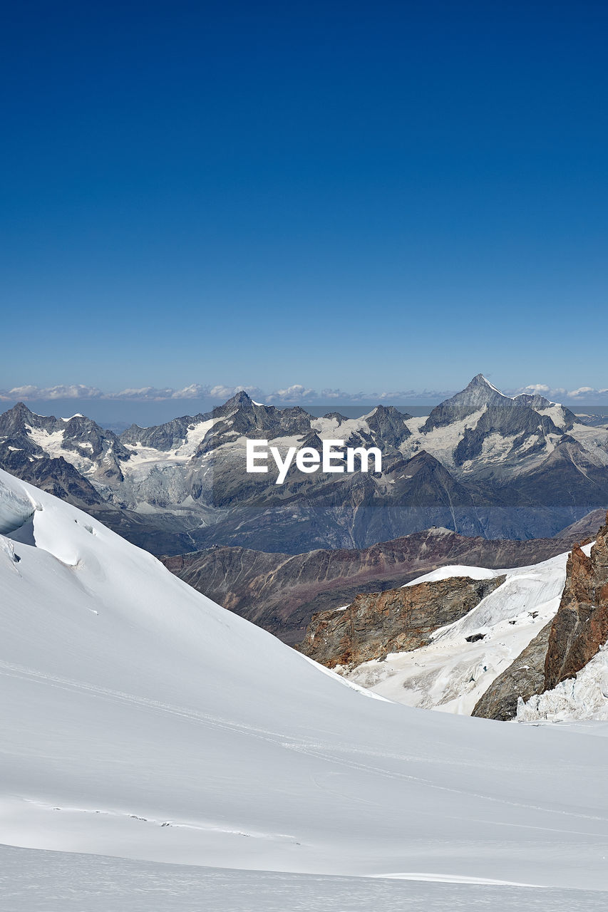 Scenic view of snowcapped mountains against blue sky