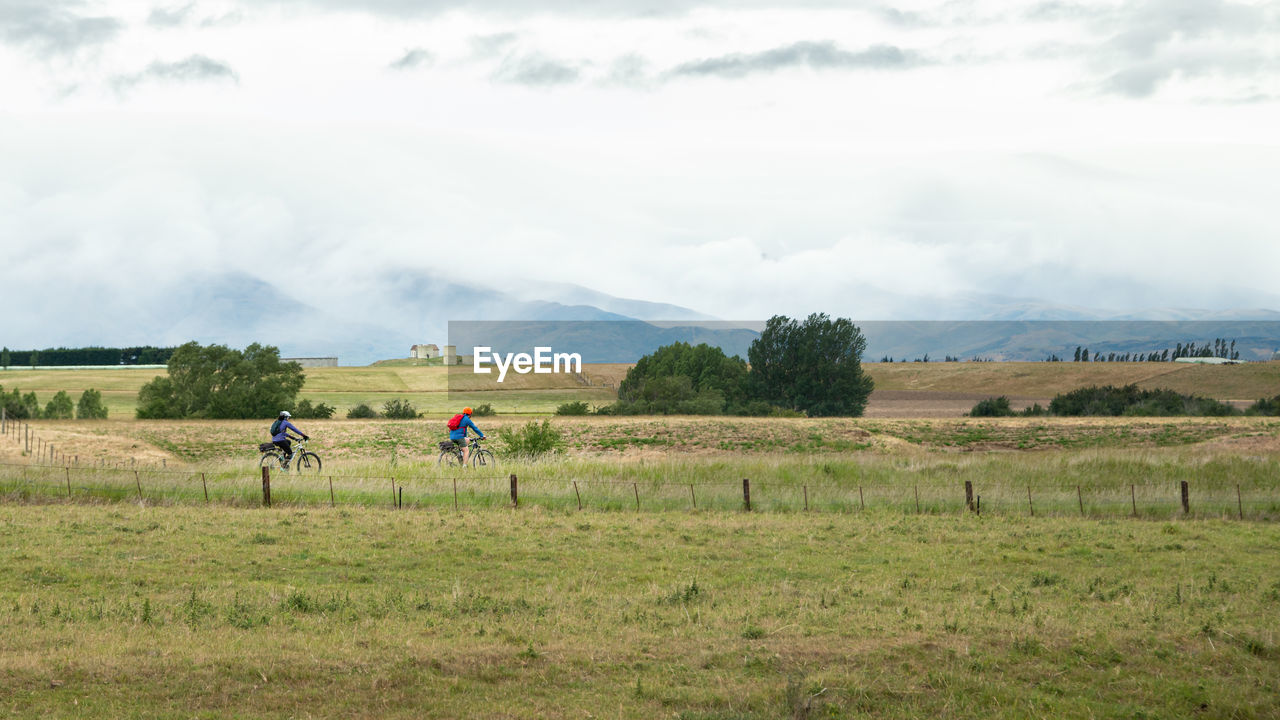 PEOPLE RIDING BICYCLE ON FIELD