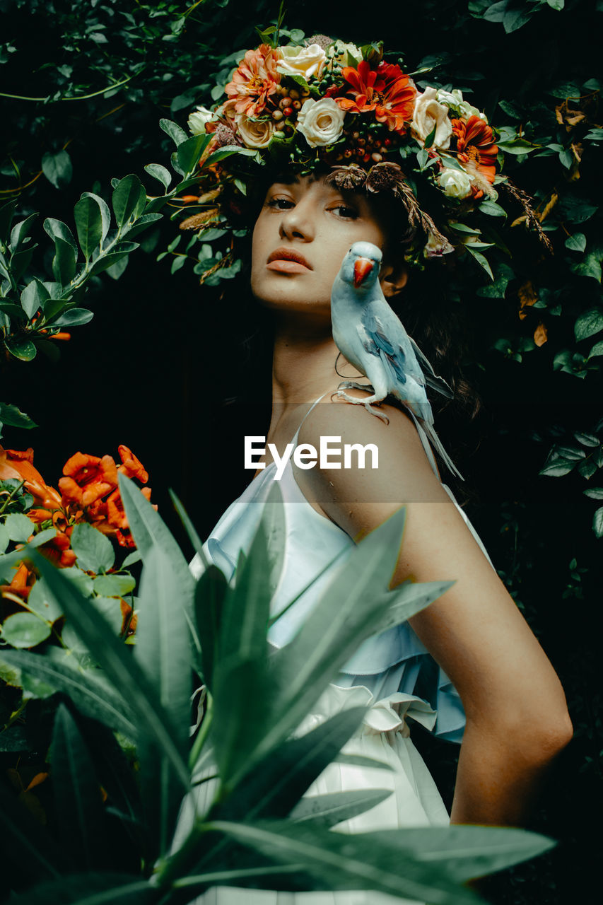 Portrait of beautiful woman standing by flowering plants