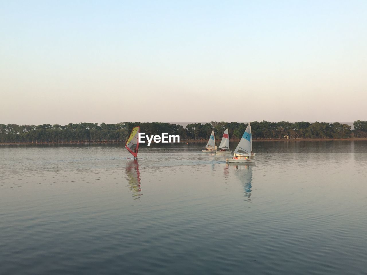 Boats on lake against clear sky during sunset