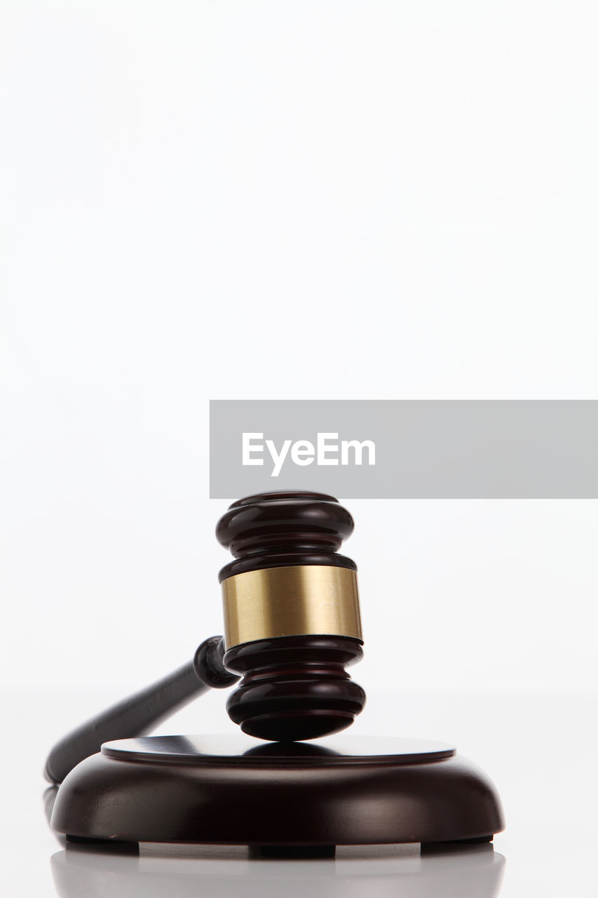 Close-up of gavel on wood against white background