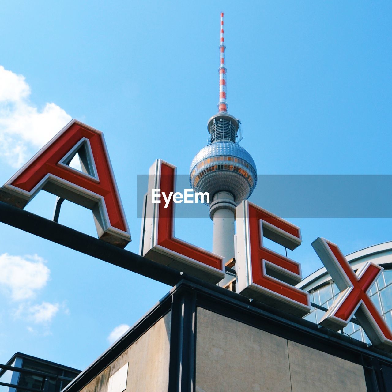 Low angle view of text by fernsehturm against blue sky