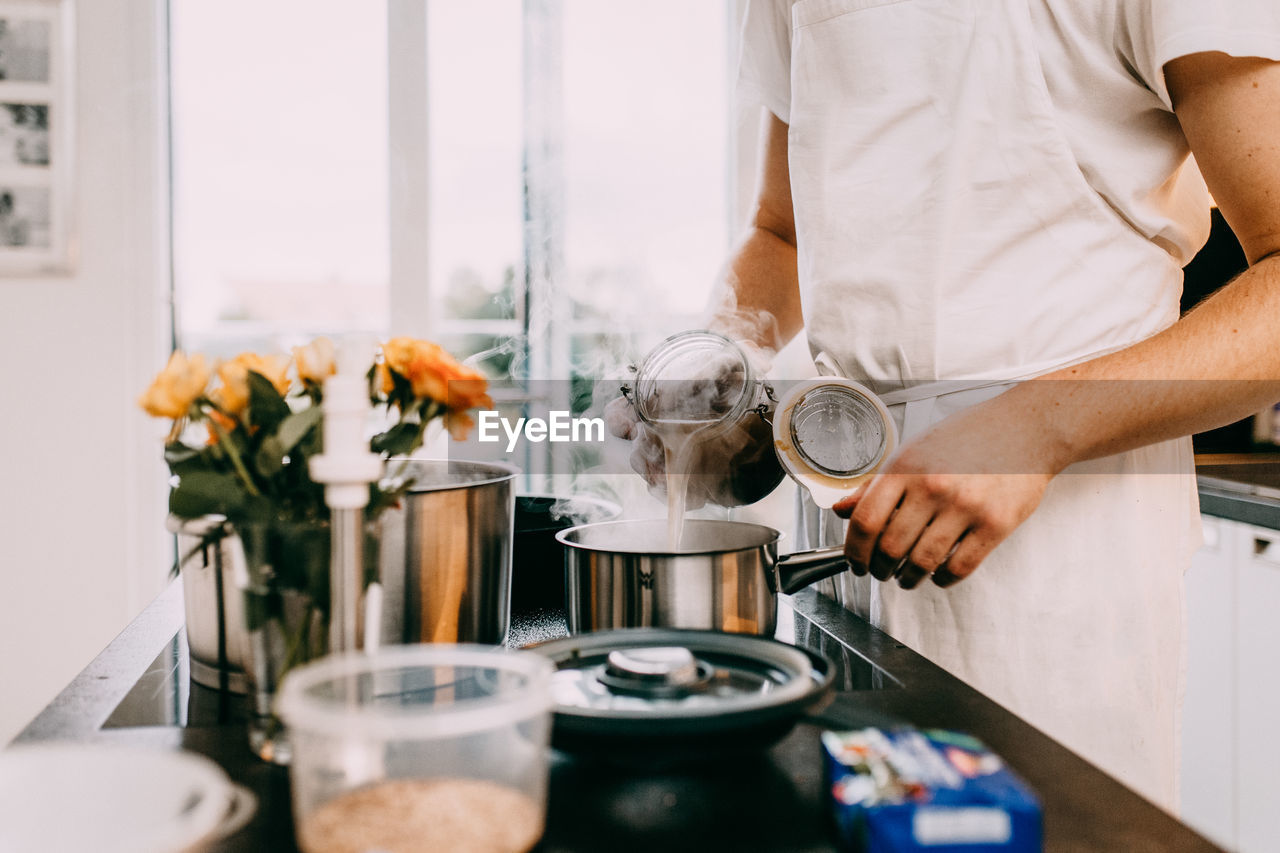 MIDSECTION OF MAN PREPARING FOOD IN KITCHEN