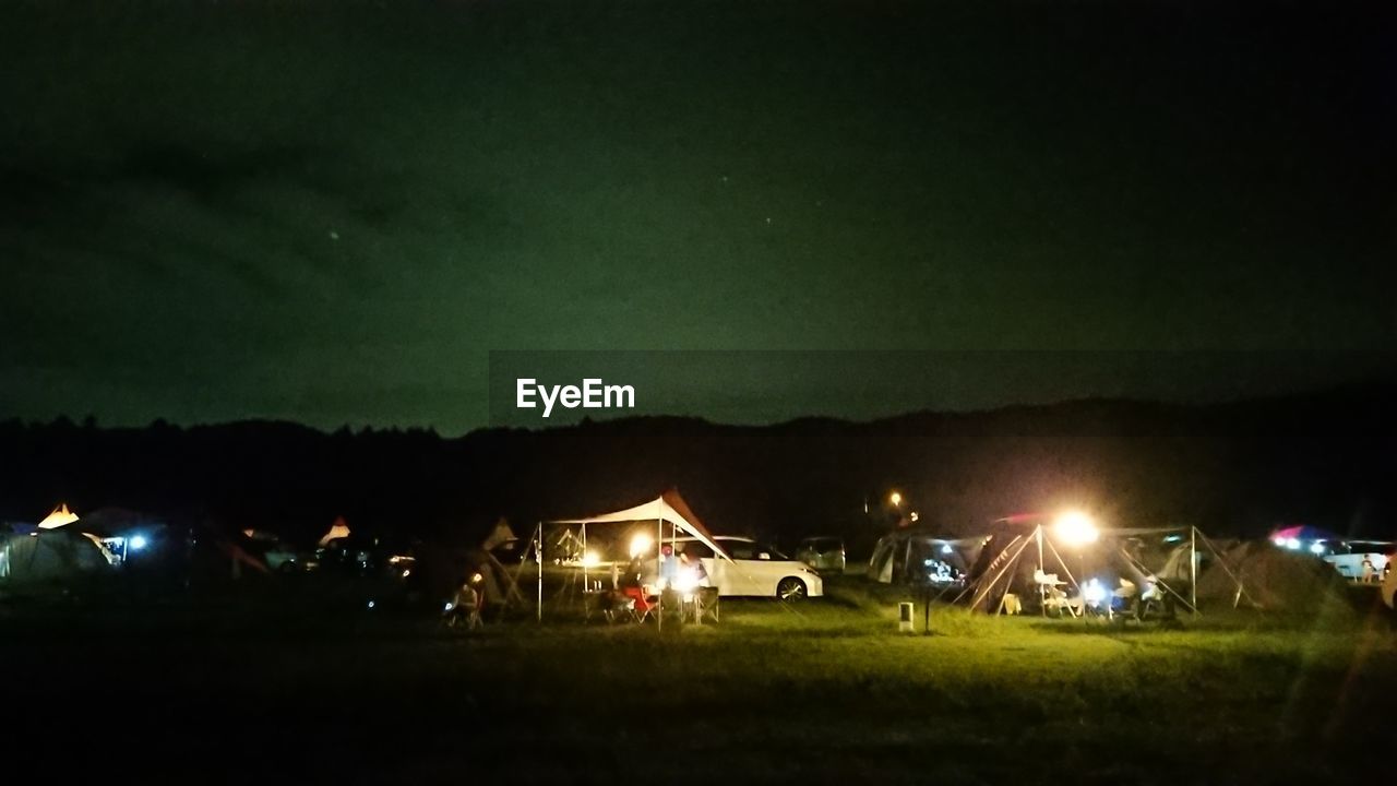 ILLUMINATED BUILDING ON FIELD AGAINST SKY AT NIGHT