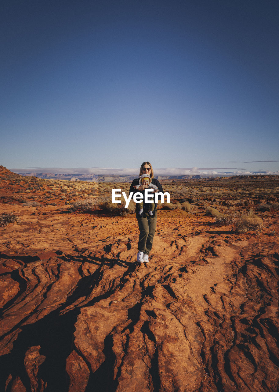 A woman with a child is standing near horseshoe bend, arizona