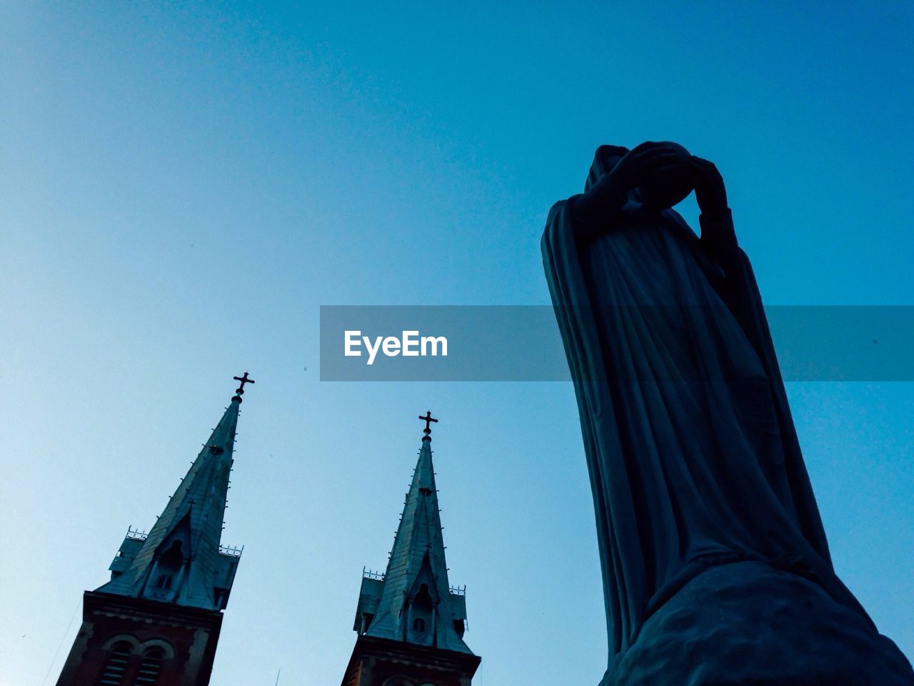 Low angle view of statue with twin church in background