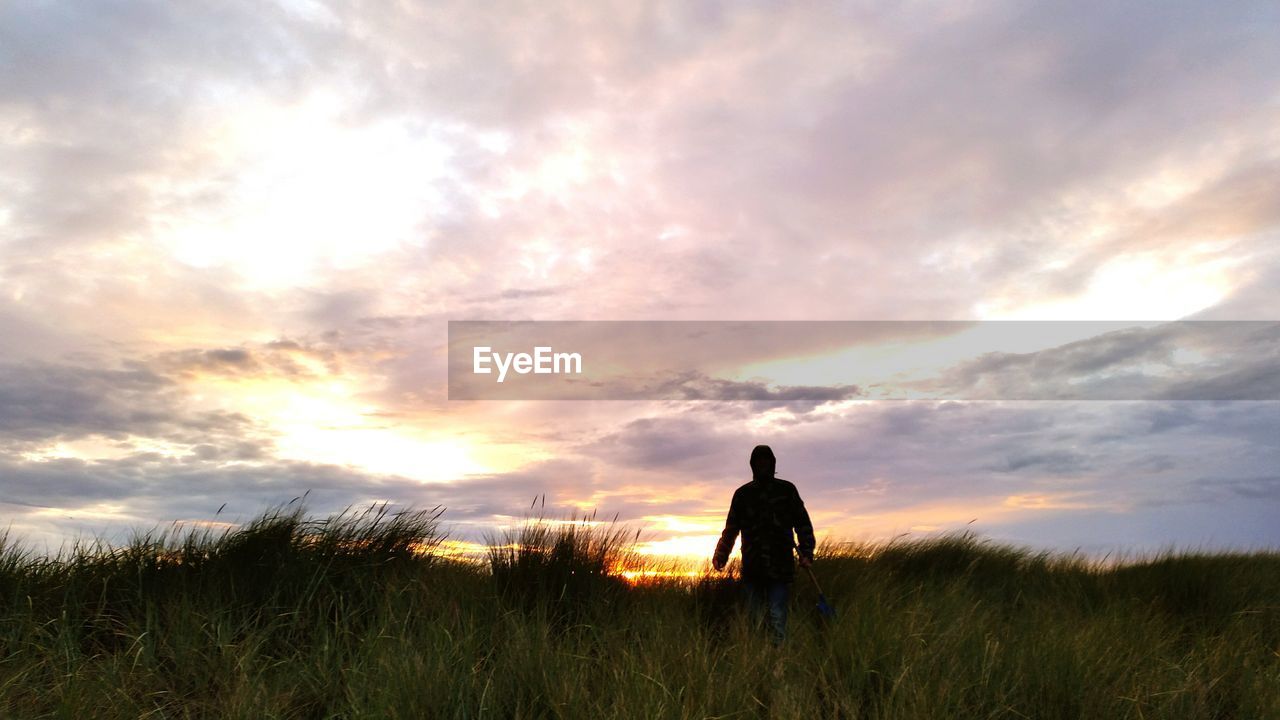 Rear view of silhouette man standing on field against sky