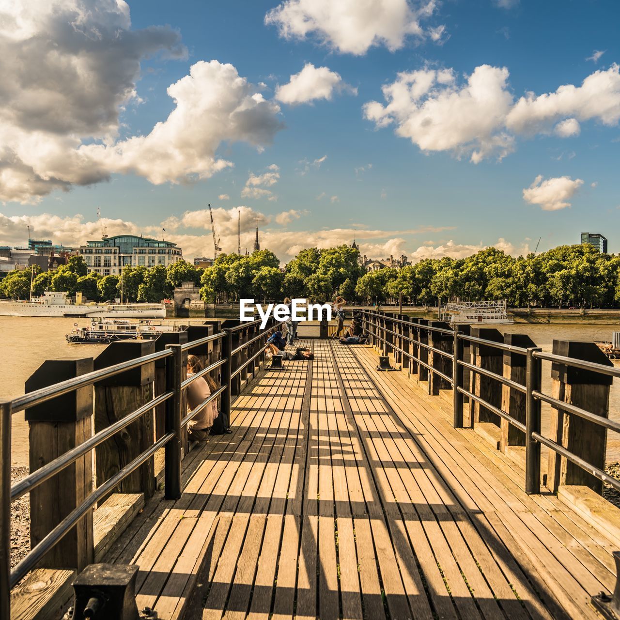 Empty pier over river against sky