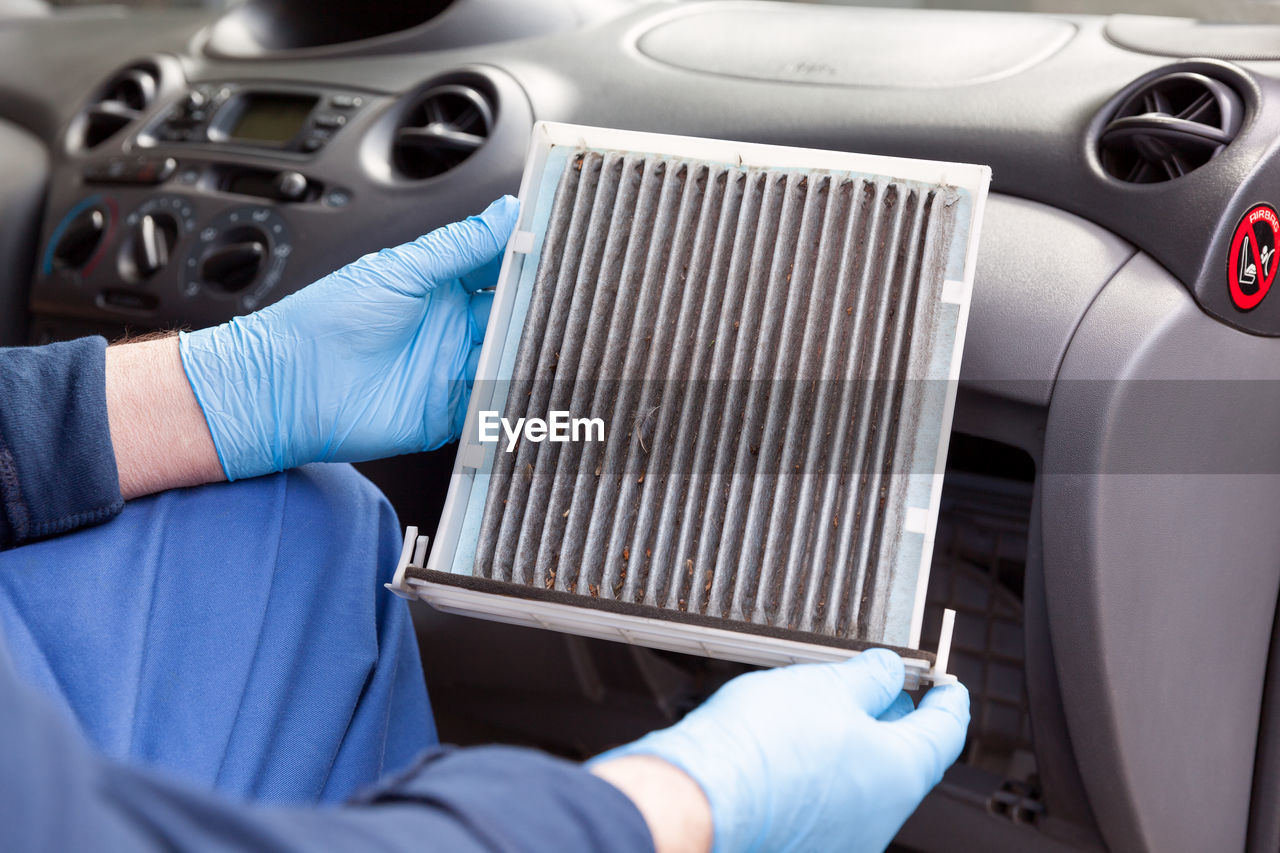 Midsection of man repairing air conditioner in car