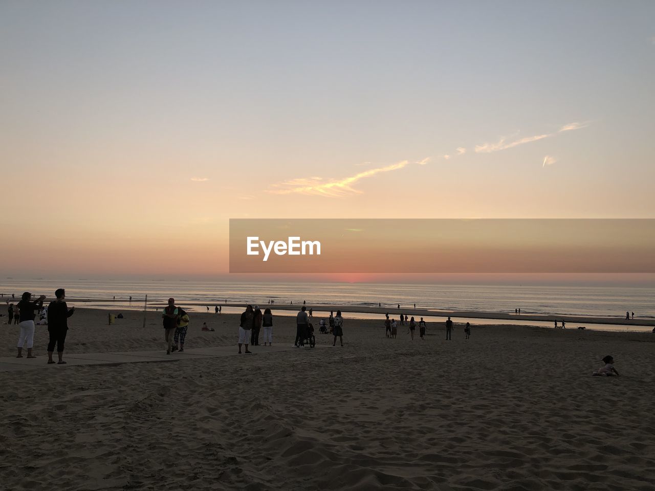 GROUP OF PEOPLE ON BEACH AT SUNSET