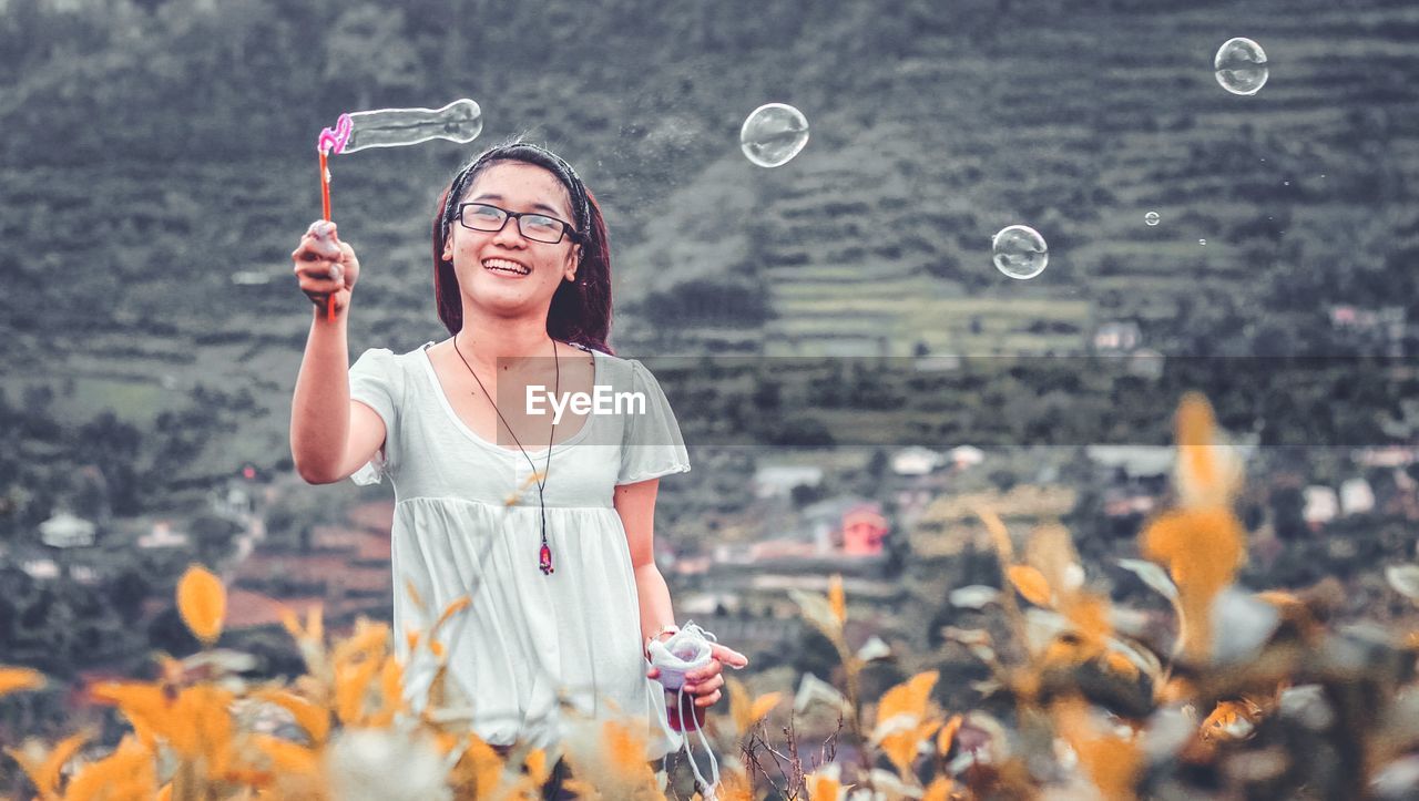 PORTRAIT OF HAPPY WOMAN STANDING OUTDOORS