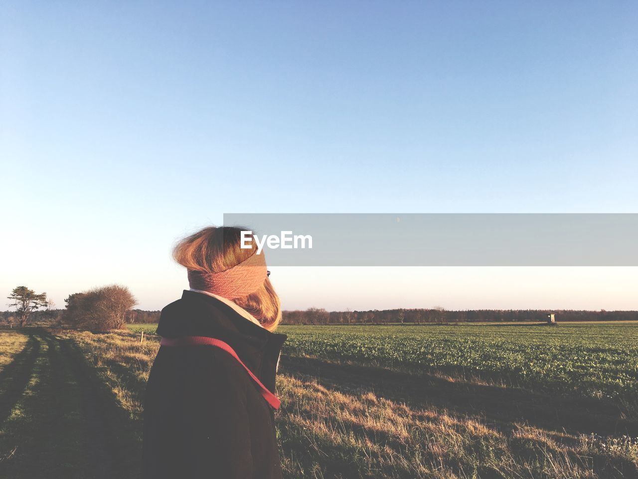 Woman standing on field against clear sky