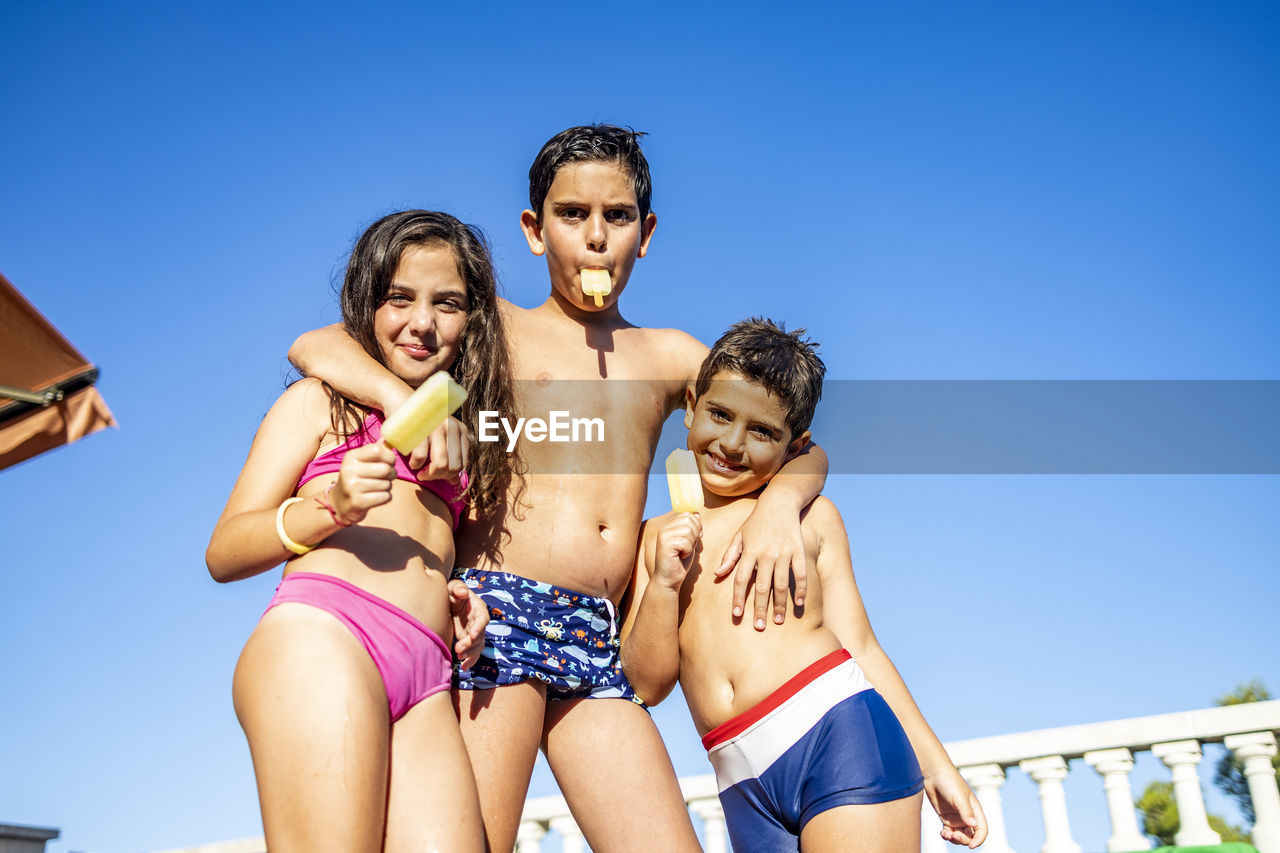Three funny kids eating an ice lolly