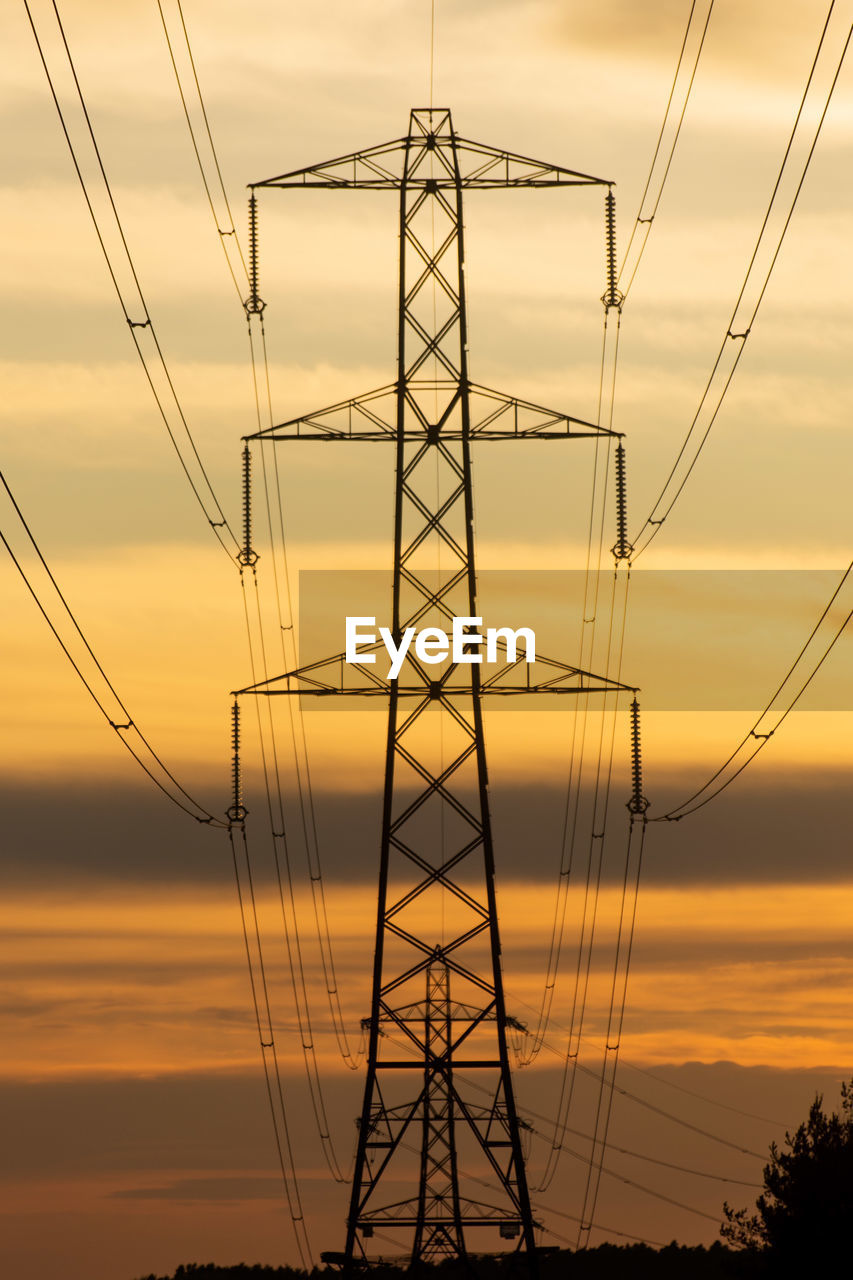 Low angle view of silhouette electricity pylon against sky during sunset