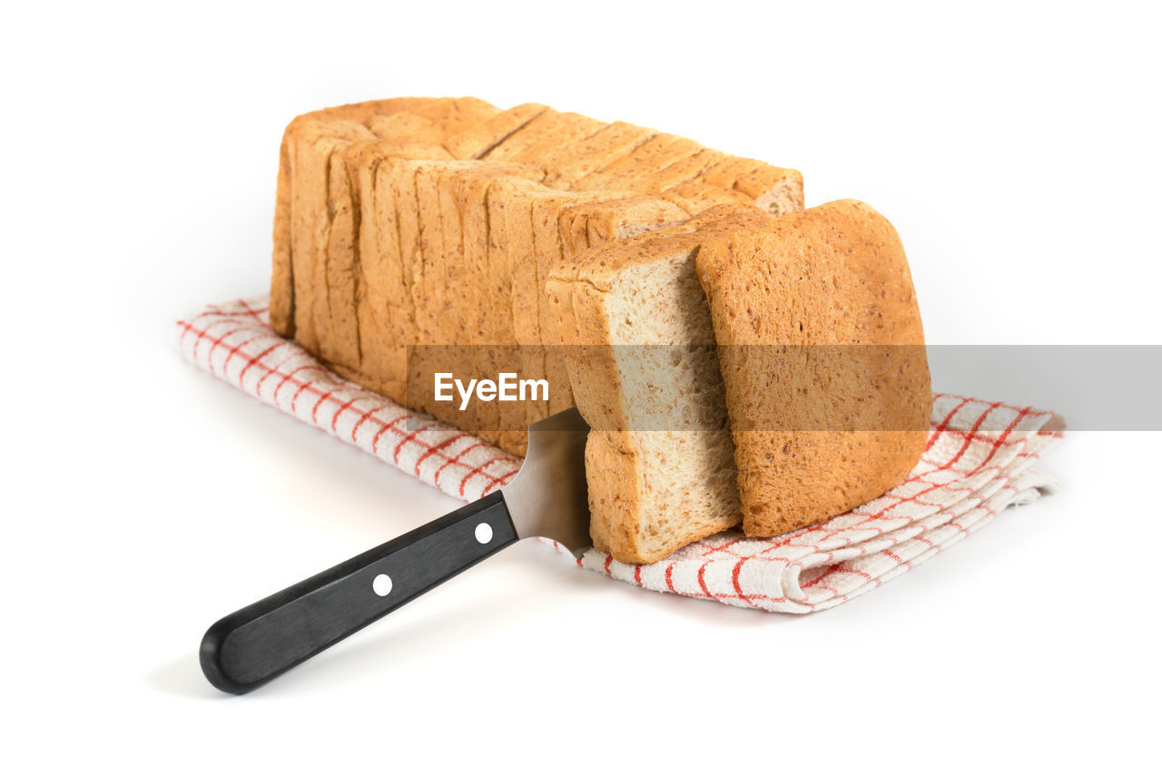 Close-up of knife amidst breads on white background