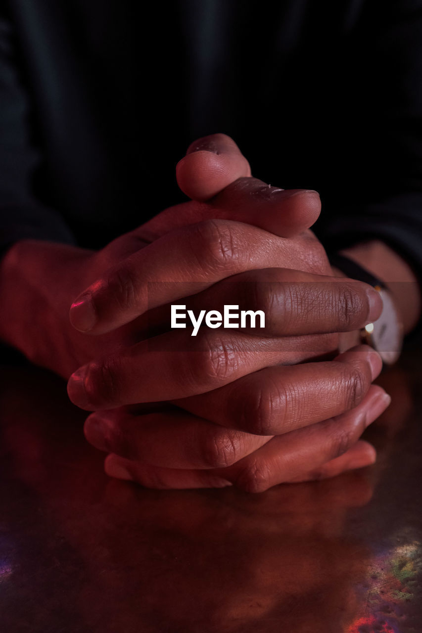 Close-up of clasped hands on table at home