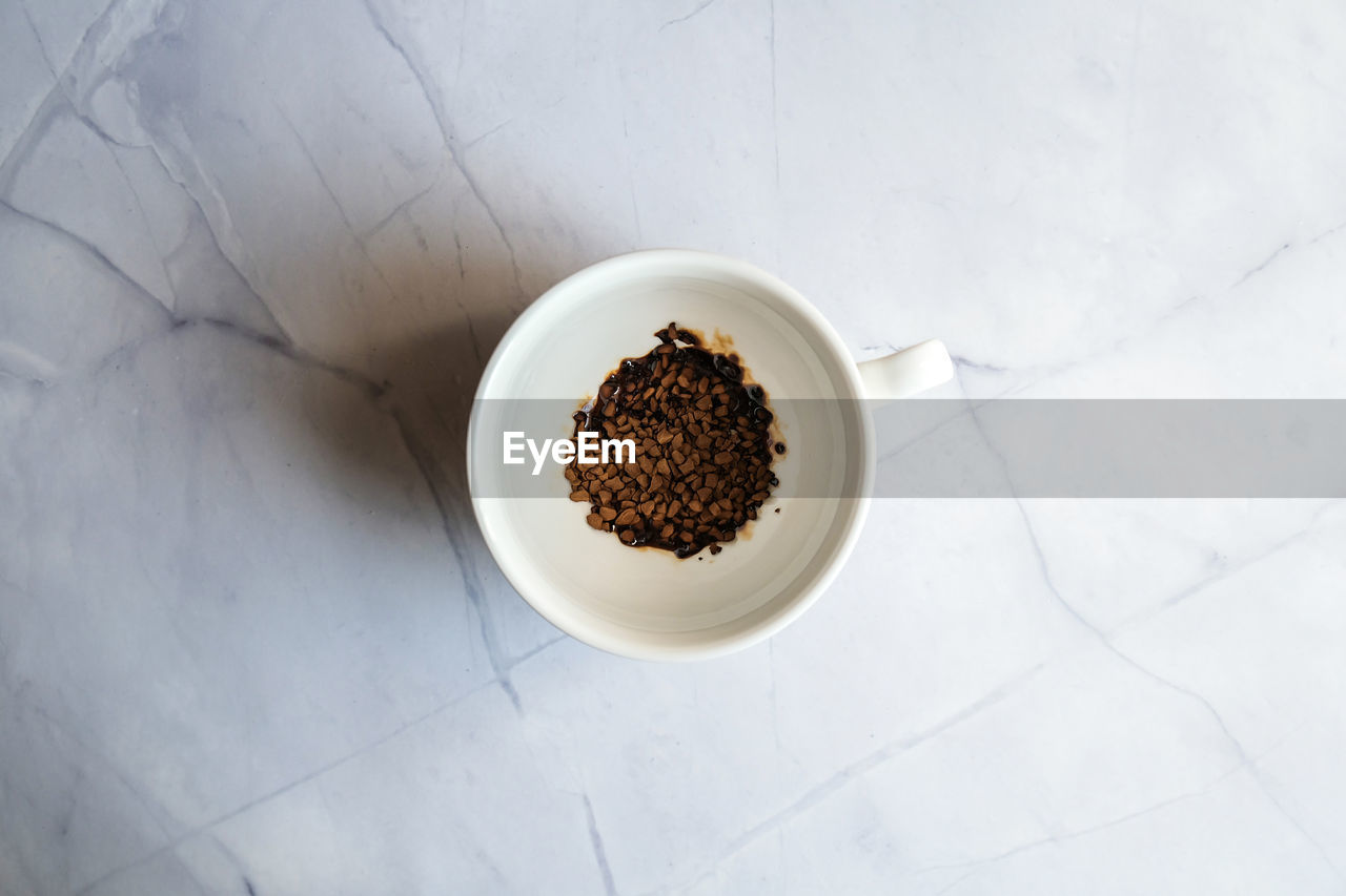 White mug with instant coffee on concrete background. morning breakfast