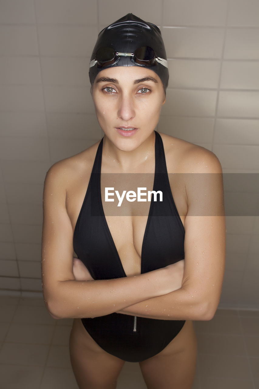 Portrait of beautiful young swimmer woman with black swimwear hat and swimming goggles
