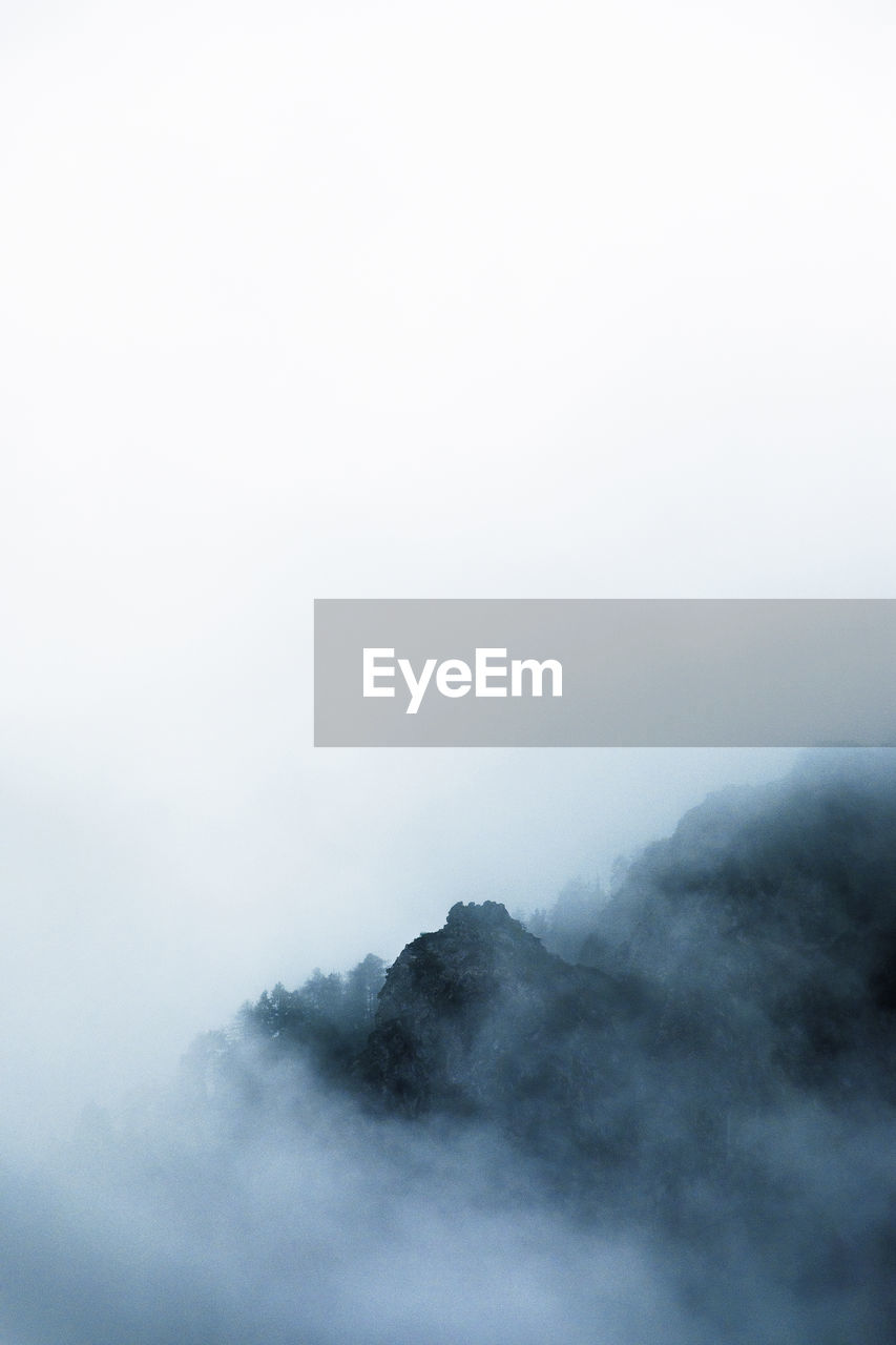 Scenic view of fog covered mountains against sky
