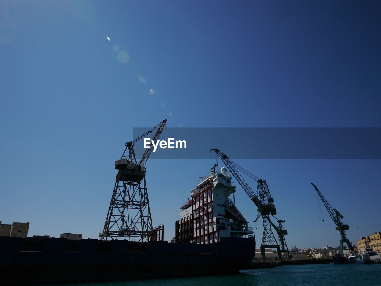 LOW ANGLE VIEW OF CRANES AGAINST CLEAR SKY