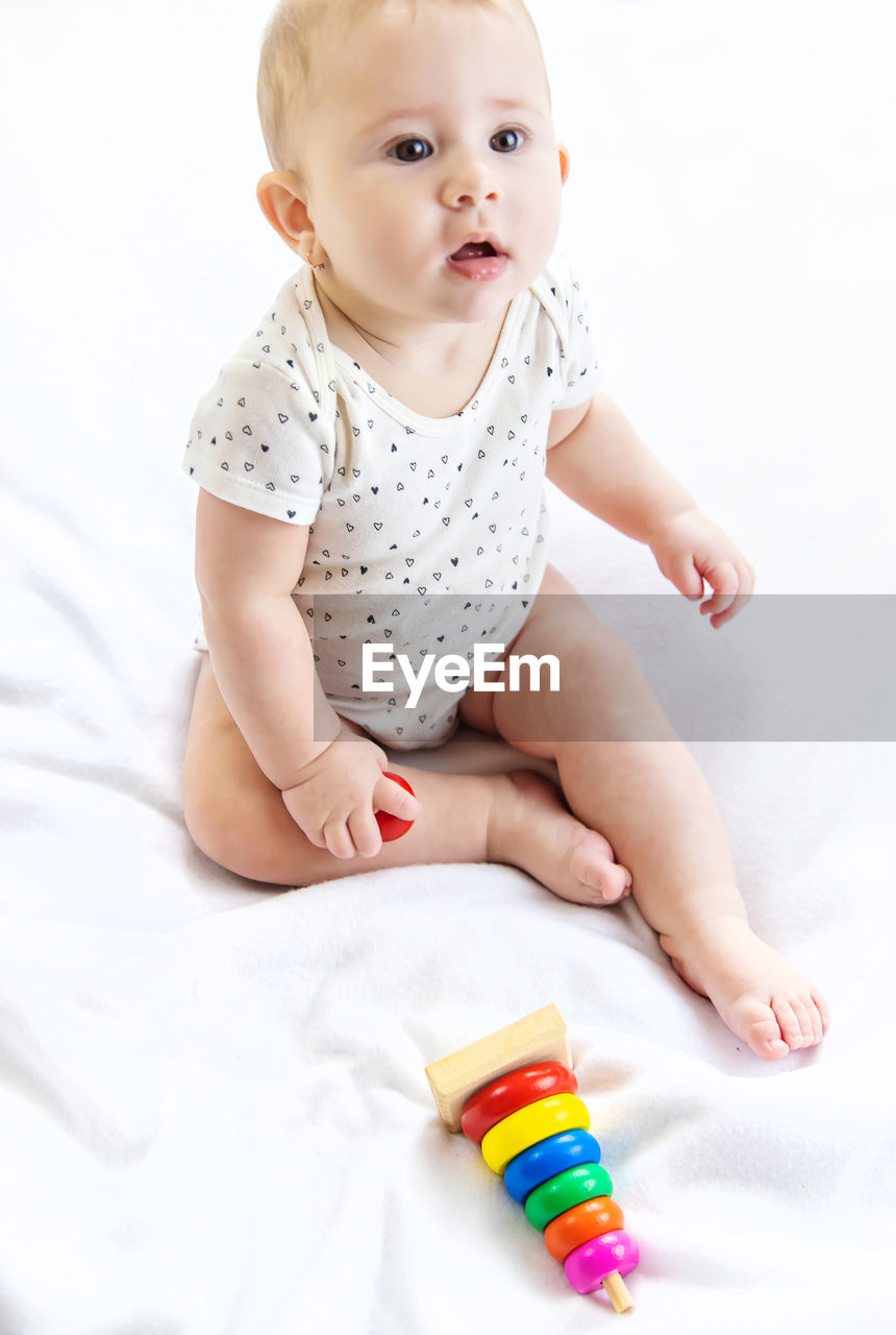 Cute baby girl with toy on bed