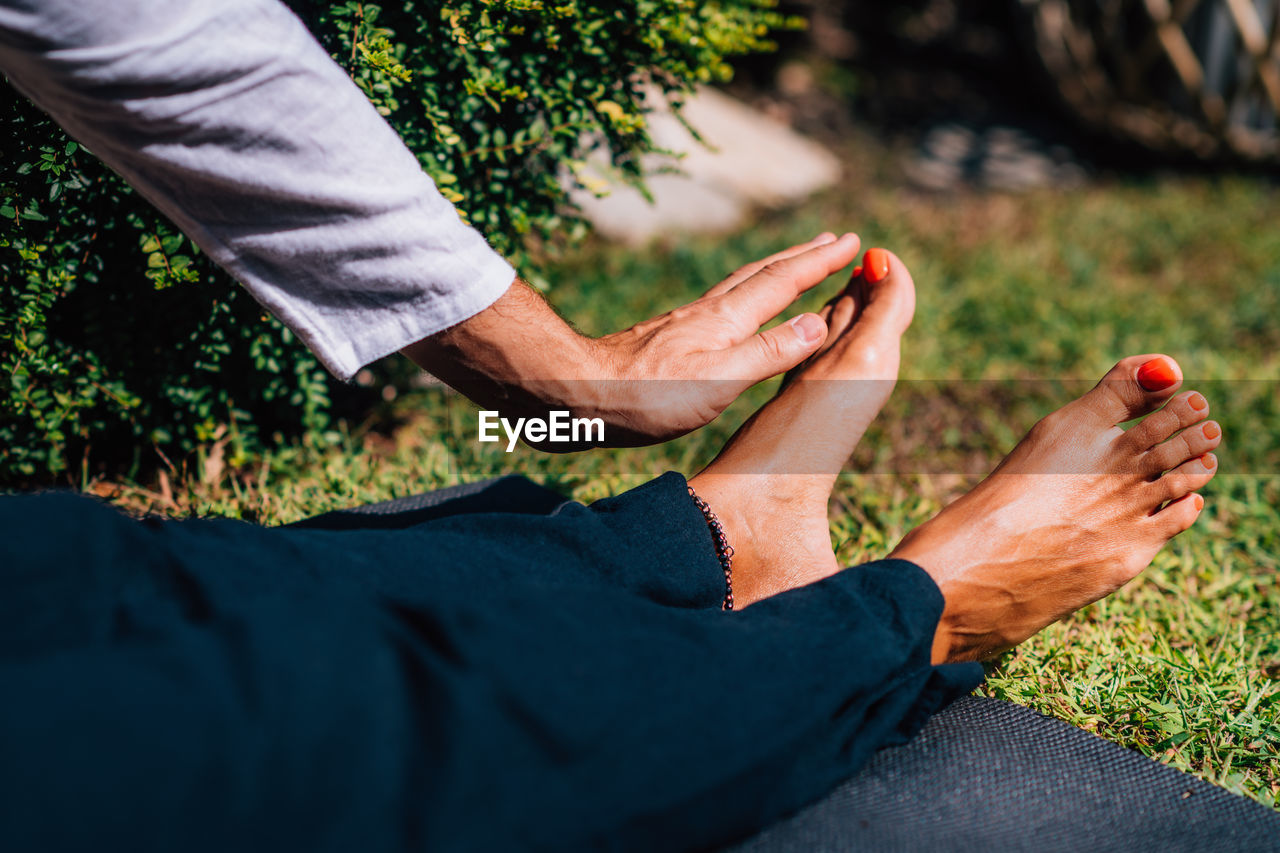 Hands of a reiki therapist healing and balancing energy points in feet. energy healing concept