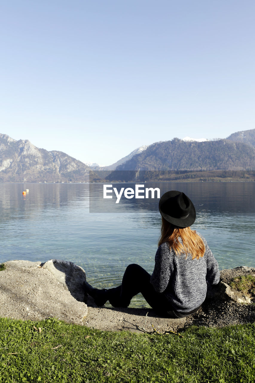 Rear view of woman looking at lake against sky